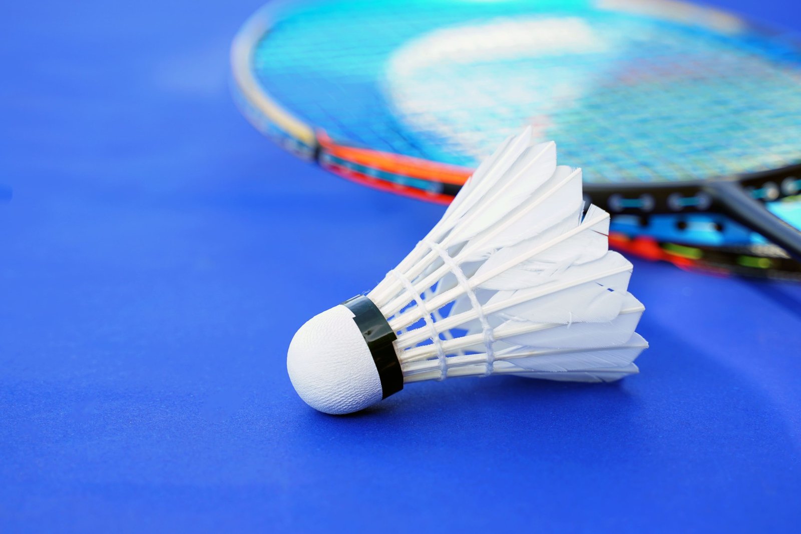 vecteezy-white-shuttlecock-on-blue-background-blurred-badminton-15696514